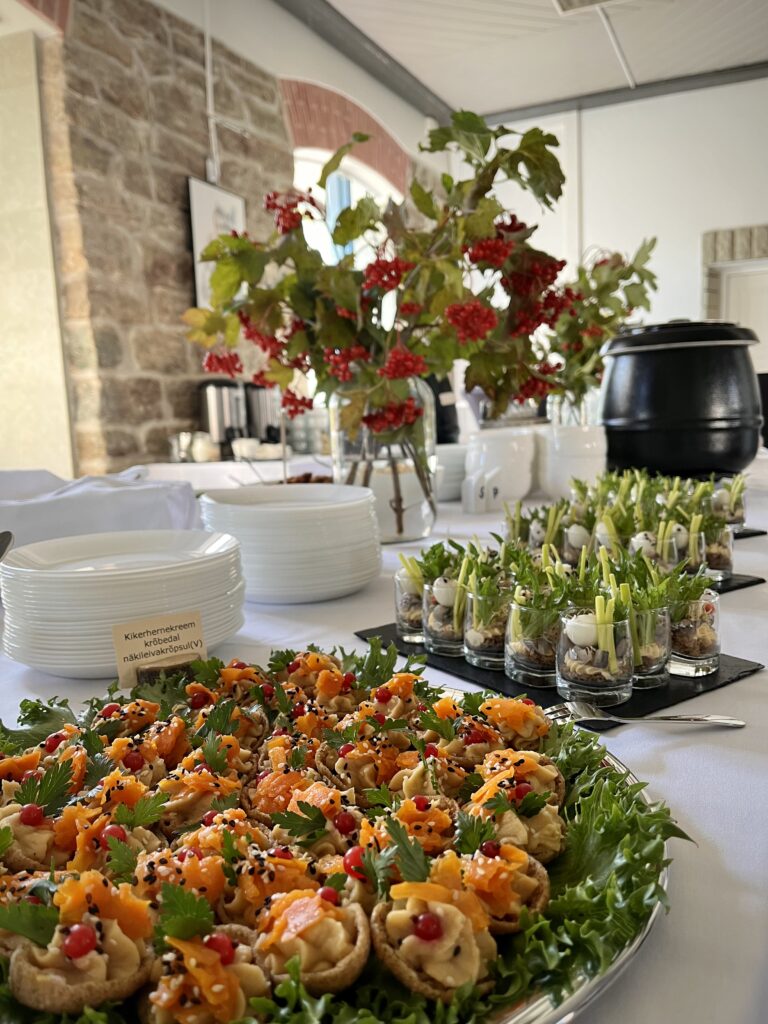 Valge linaga peolaud kaetud Catering Kene suupistete, inventari ja dekoratsioonidega.